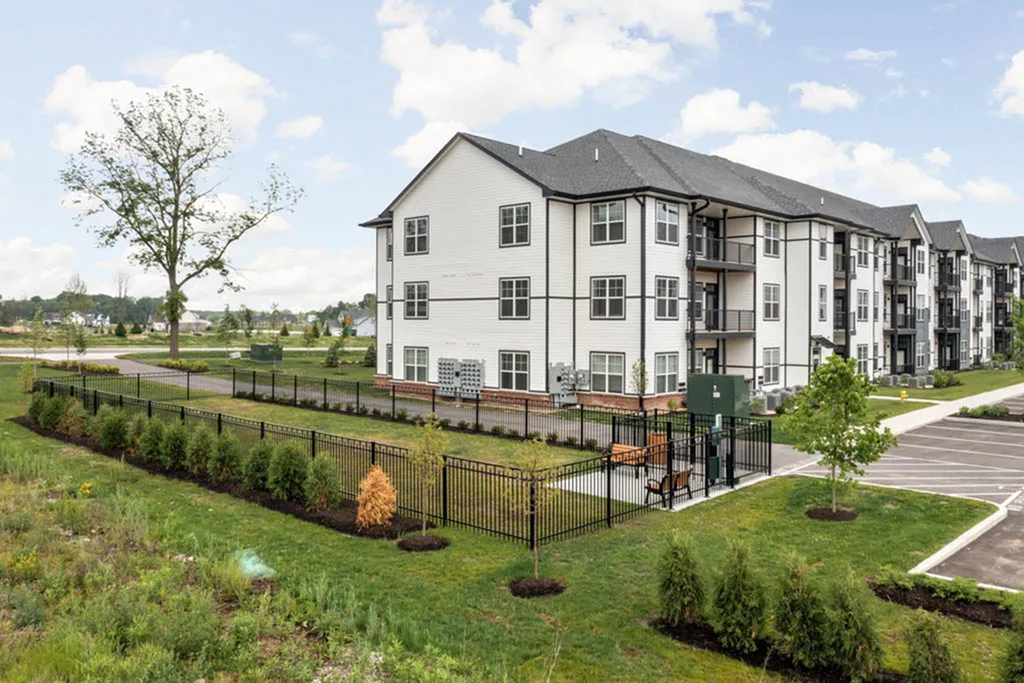 Modern apartment complex with elegant design, surrounded by lush greenery and a well-maintained garden, offering a serene residential environment.