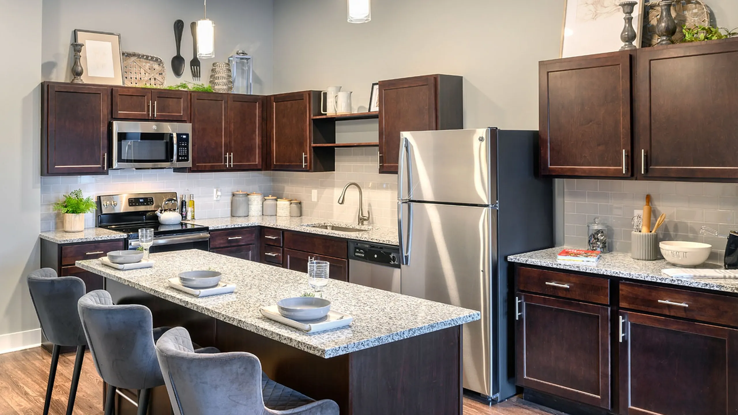 Modern kitchen with sleek dark wood cabinets, granite countertops, and stainless steel appliances, featuring a large island with stylish bar seating.