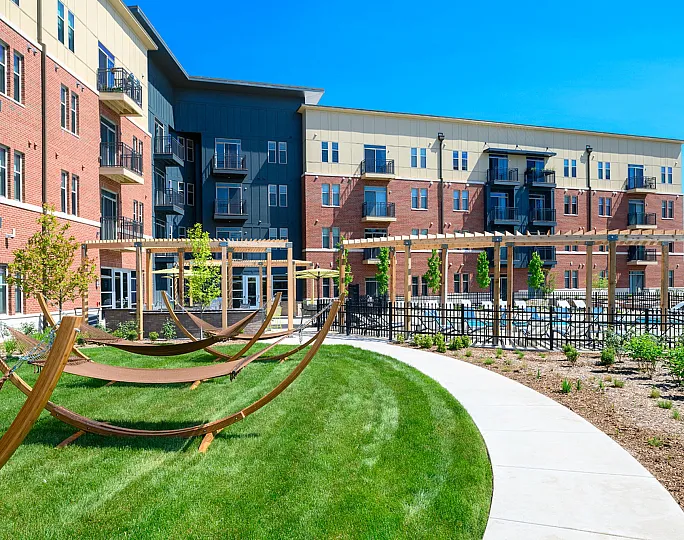 Vibrant apartment complex with modern balconies, lush green lawn, and inviting hammocks for relaxation.