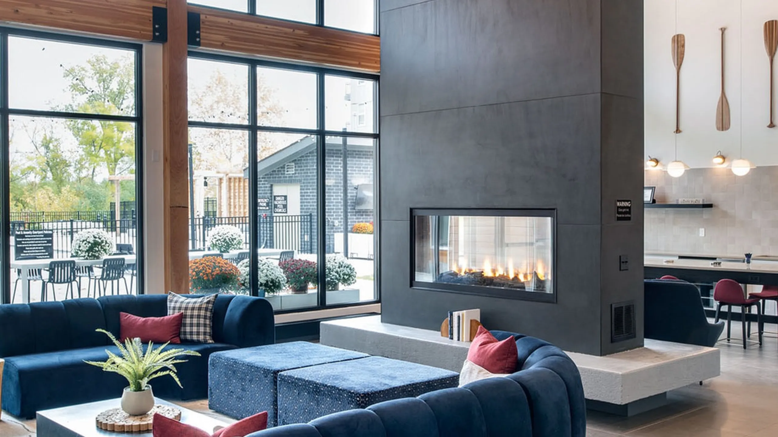Modern lounge with elegant high ceilings, stylish chandelier, and a cozy central fireplace, perfect for relaxing and social gatherings.