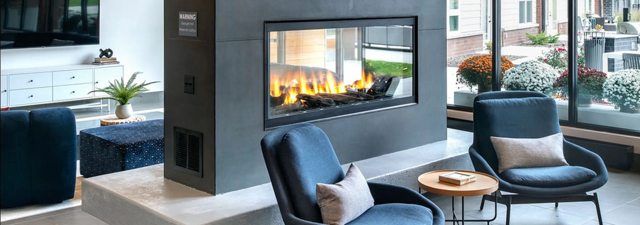 Luxurious living room with a stunning double-sided fireplace, stylish seating, and expansive windows showcasing a modern architectural view.