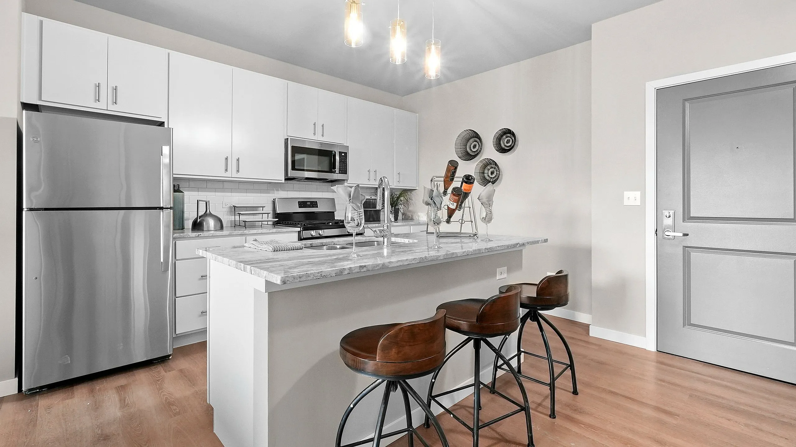Modern kitchen with sleek white cabinetry, stainless steel appliances, and a chic breakfast bar with stylish barstools.