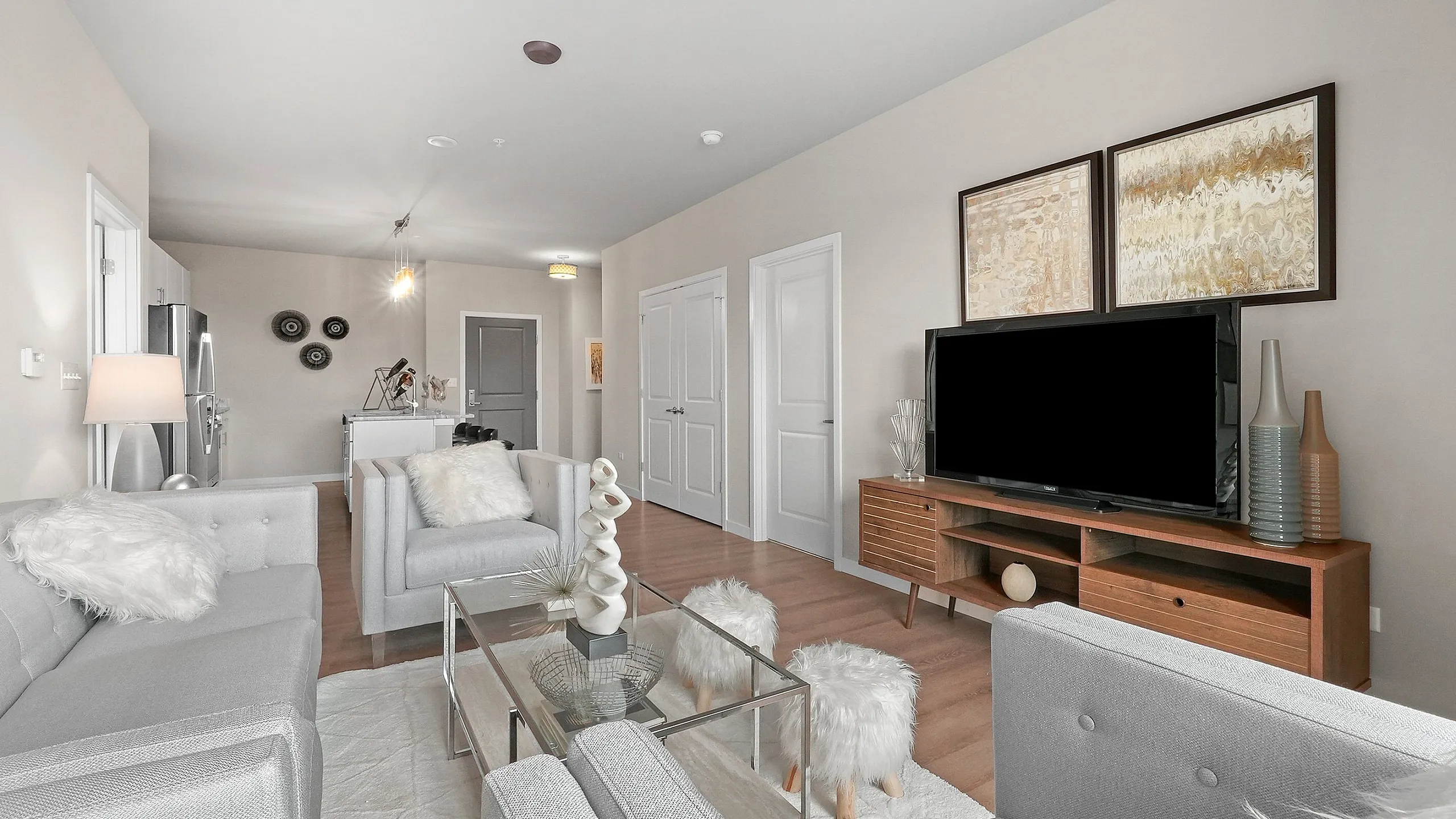 Elegant living room with modern decor, featuring plush gray seating, artistic accents, and a sleek entertainment unit.