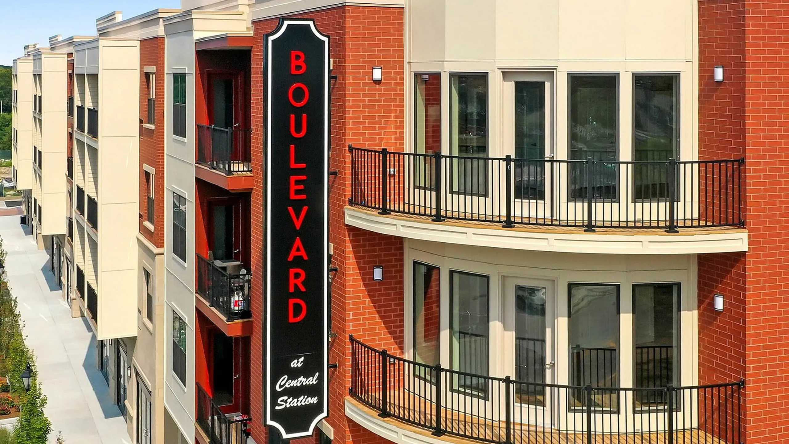Modern apartment building exterior with brick facade, stylish balconies, and a prominent Boulevard sign, nestled in a serene urban setting.