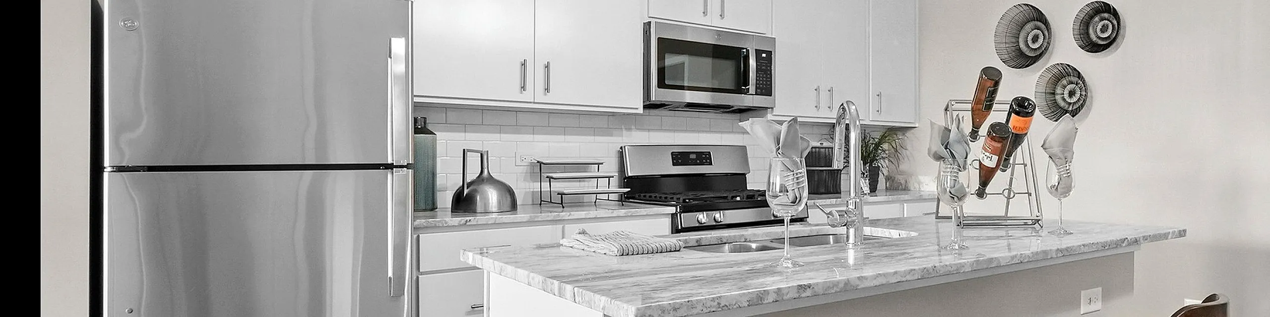 Chic and modern kitchen with sleek stainless steel appliances, elegant white cabinetry, and a stylish breakfast bar with barstools.