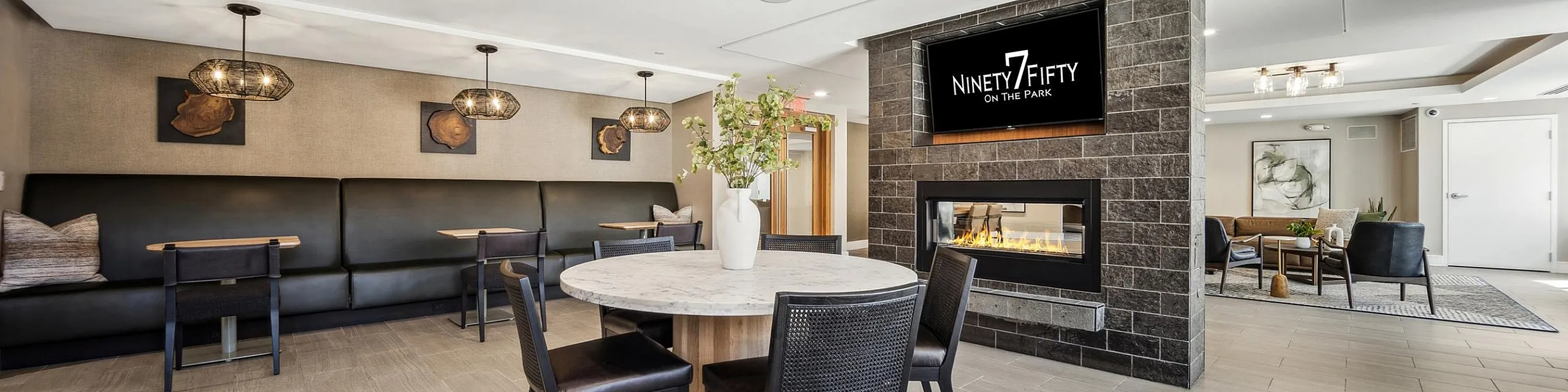 Modern and inviting communal space at Ninety7Fifty on the Park featuring a cozy fireplace, elegant seating, and stylish lighting.