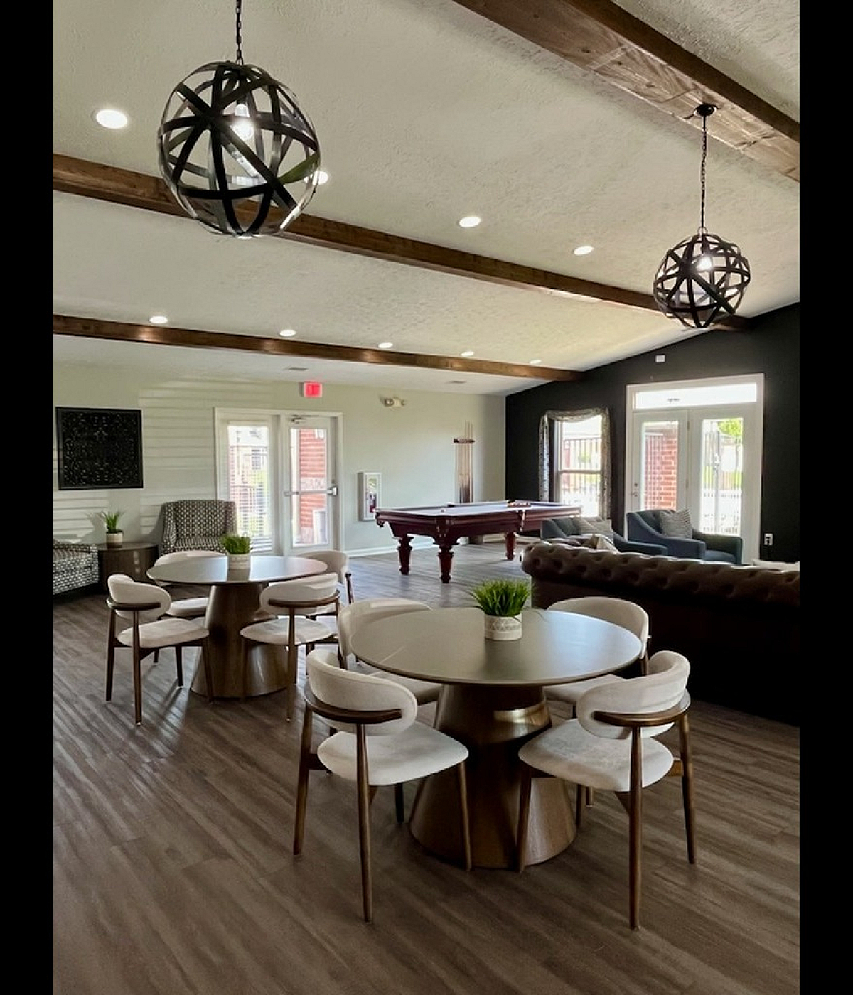 Chic communal lounge with modern decor, featuring stylish round tables, elegant lighting, and a pool table.