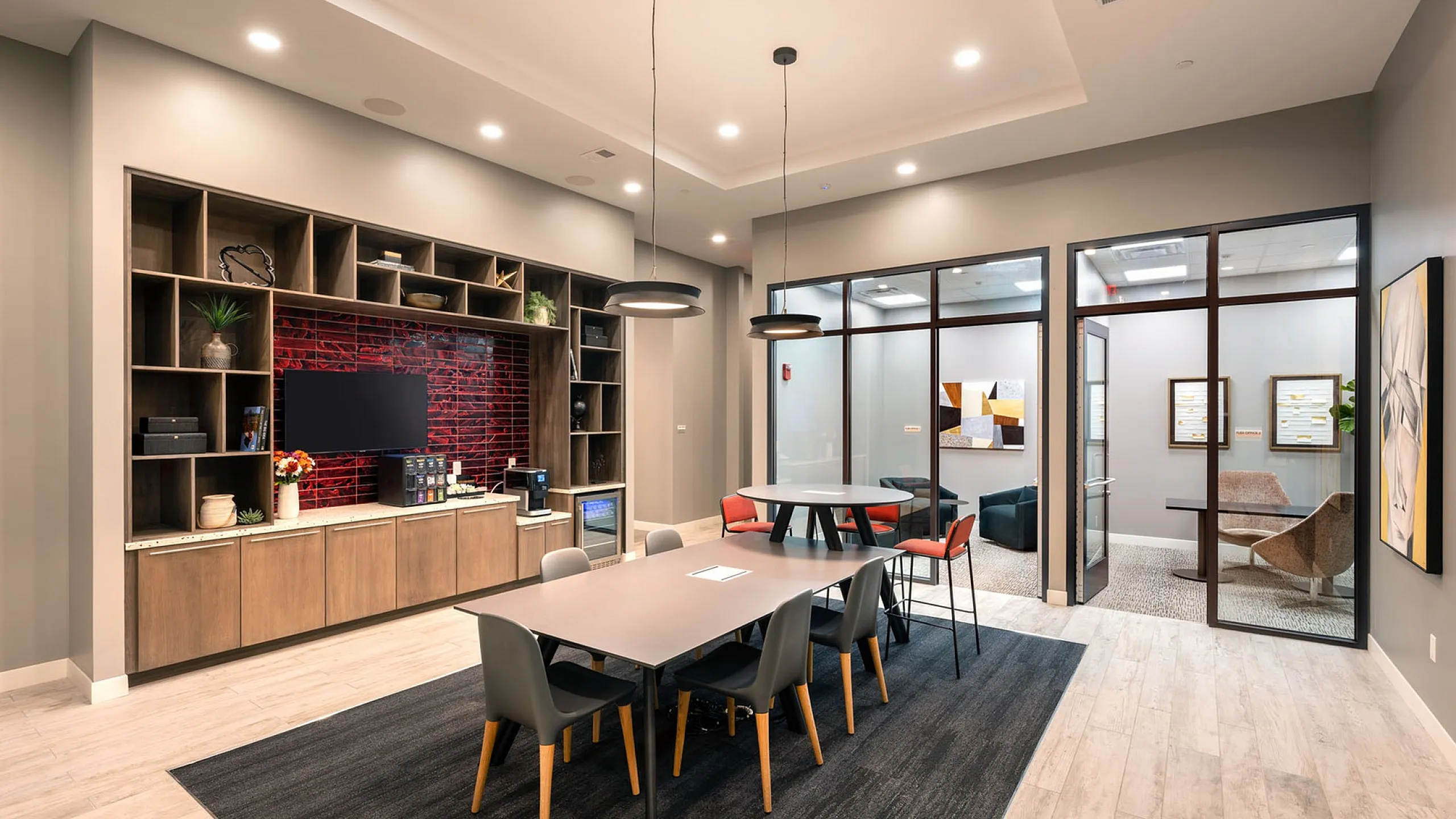 Modern meeting space featuring sleek furniture, ambient lighting, and bold red accent wall creating a stylish and inviting atmosphere.