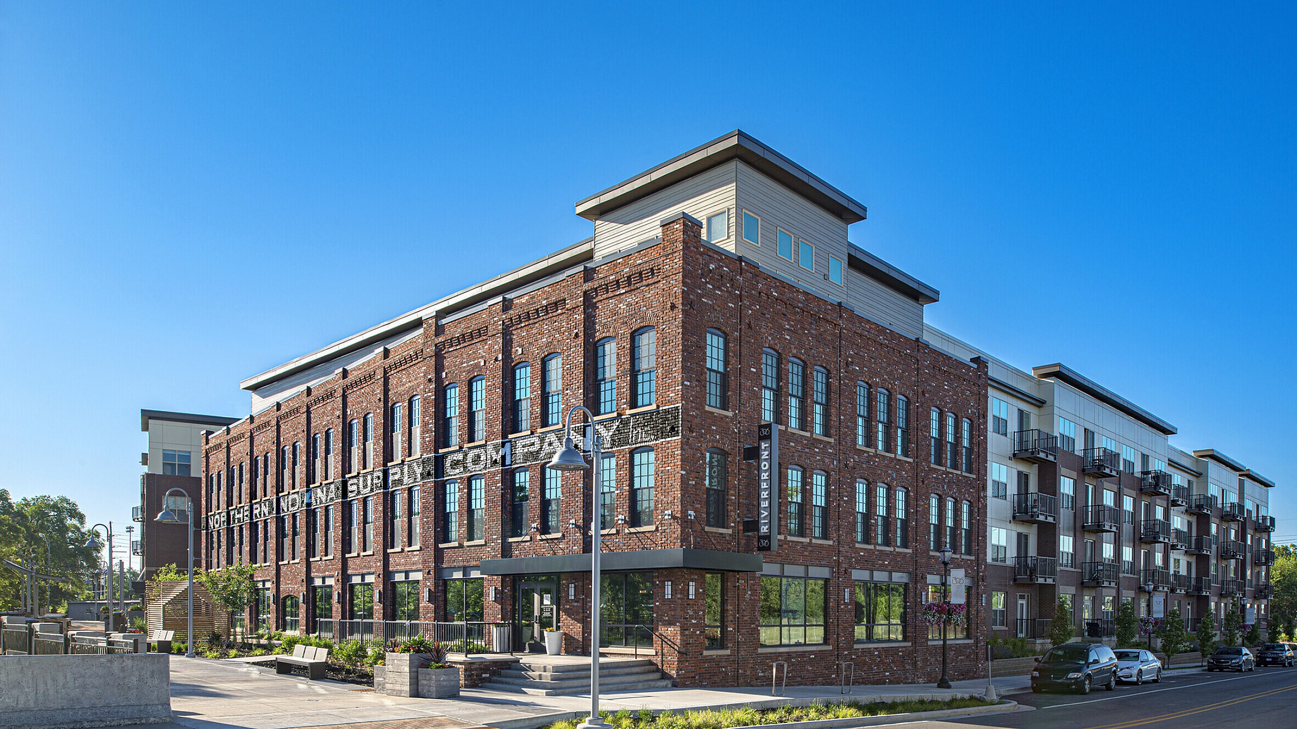 Charming red brick apartment building with modern balconies, set against a vibrant blue sky in an urban setting.