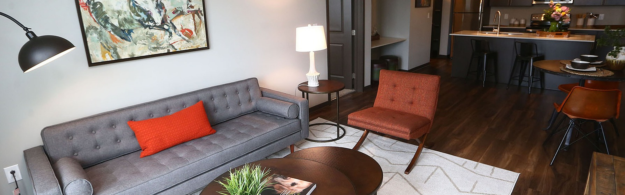 Chic apartment living room with modern decor, stylish furniture, and an open-plan kitchen layout showcasing sleek cabinetry and ambient lighting.