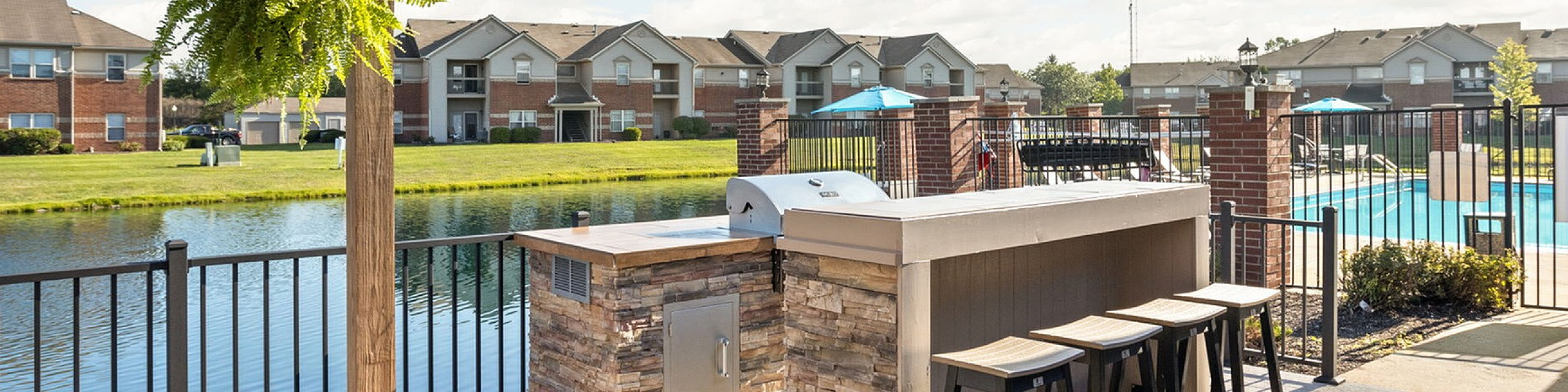 Charming outdoor patio with pergola overlooking a serene pond and modern swimming pool, ideal for relaxing and entertaining.