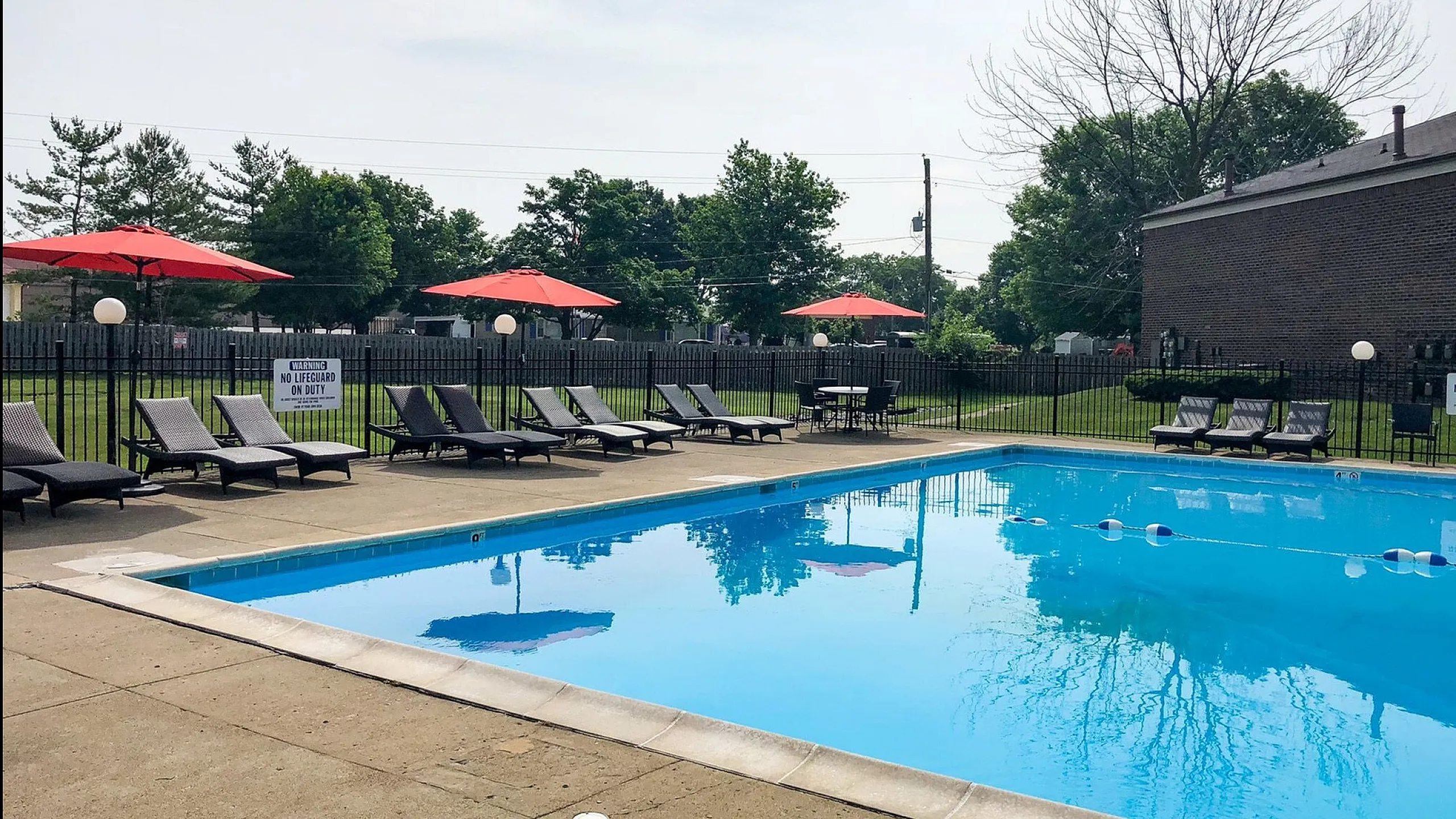 Inviting outdoor pool area with stylish lounge chairs and vibrant red umbrellas, perfect for relaxation and leisure.