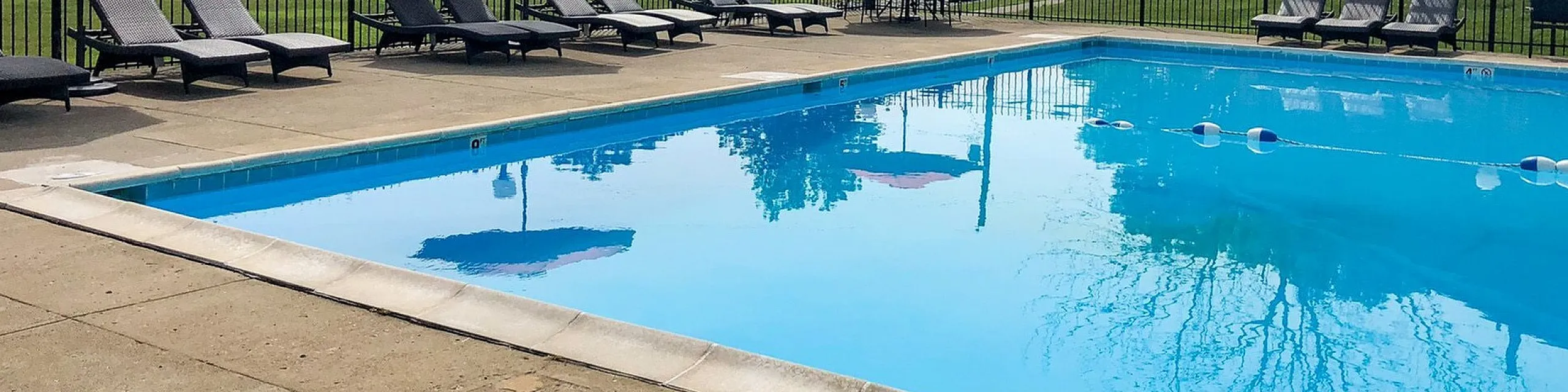 Inviting outdoor swimming pool with stylish loungers and red umbrellas, perfect for relaxation and leisure.