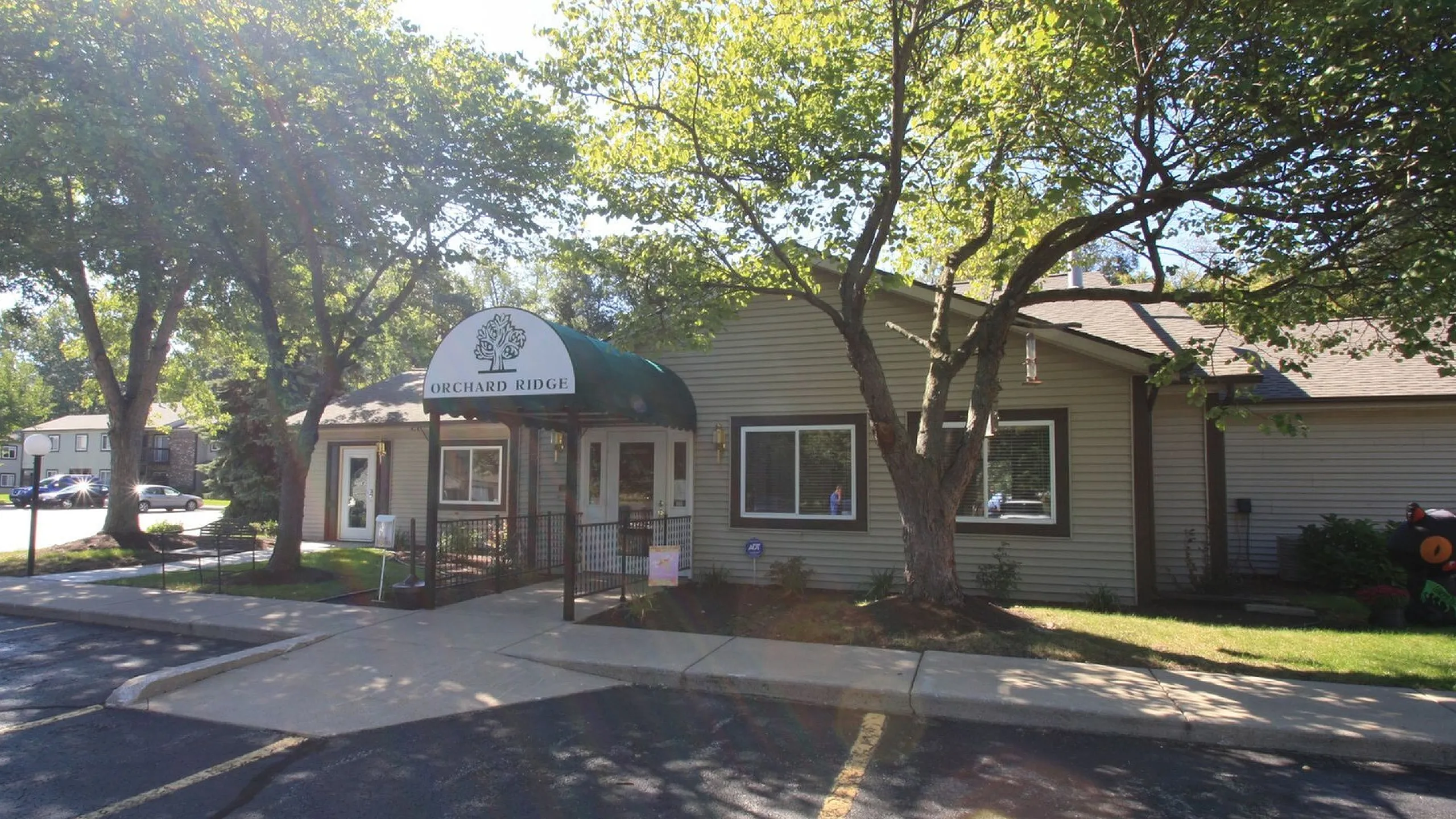 Welcoming exterior of Orchard Ridge showing charming architecture surrounded by lush trees and well-maintained landscaping.