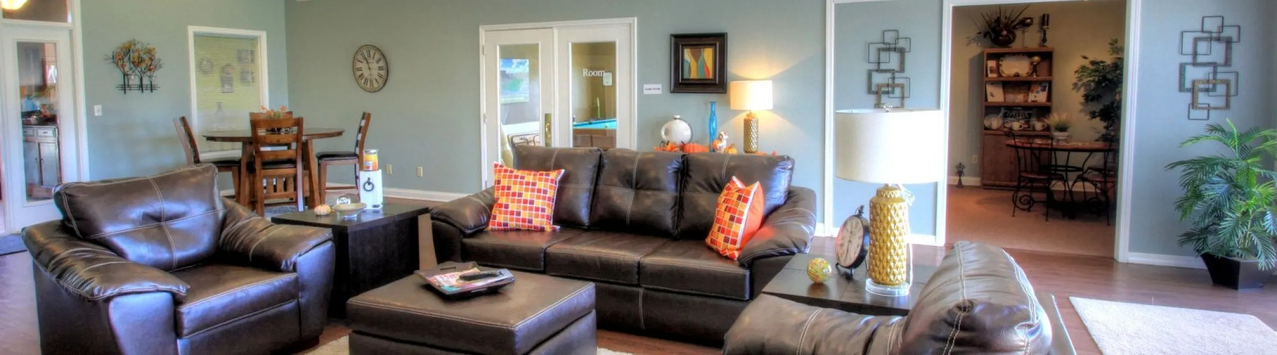 Inviting living room with cozy leather seating, vibrant accent pillows, and warm lighting, perfect for relaxation and entertaining.