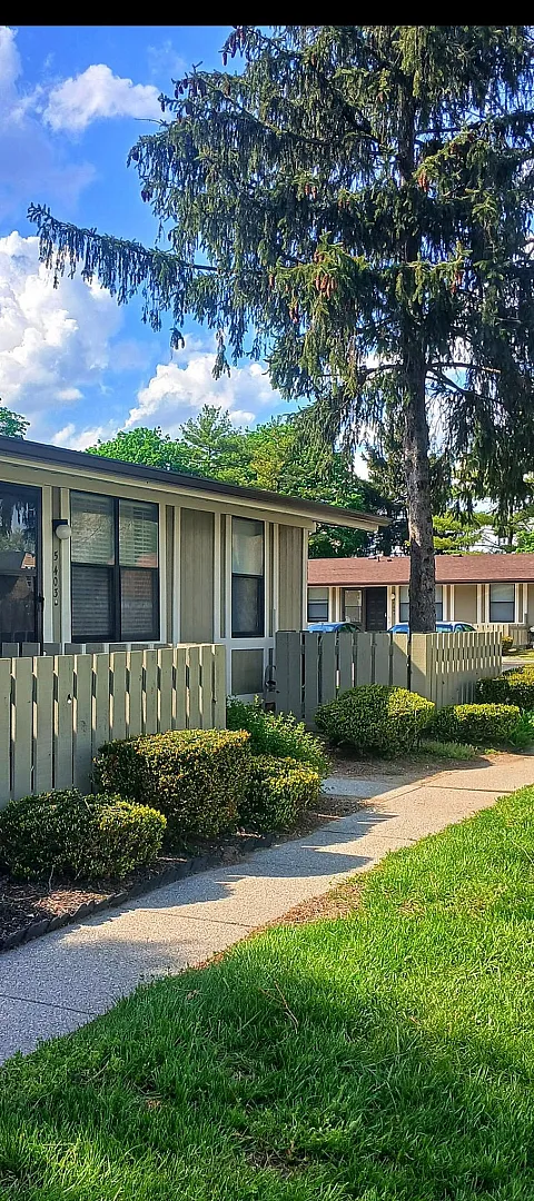 Charming single-story apartment with lush landscaping and a peaceful exterior view, perfect for serene living.