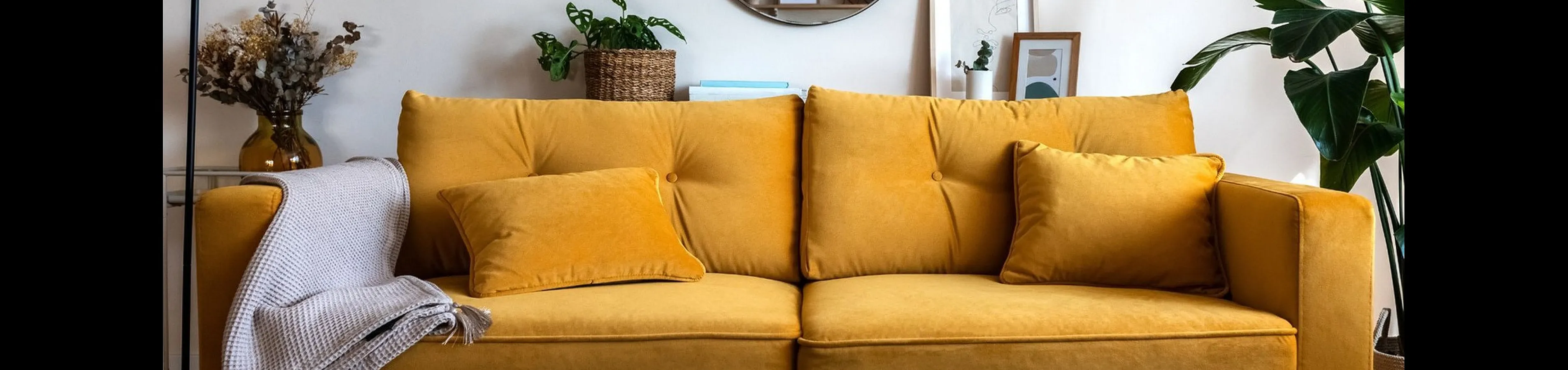 Inviting living room with a vibrant yellow sofa, elegant decor, and lush green plants creating a warm and stylish ambiance.