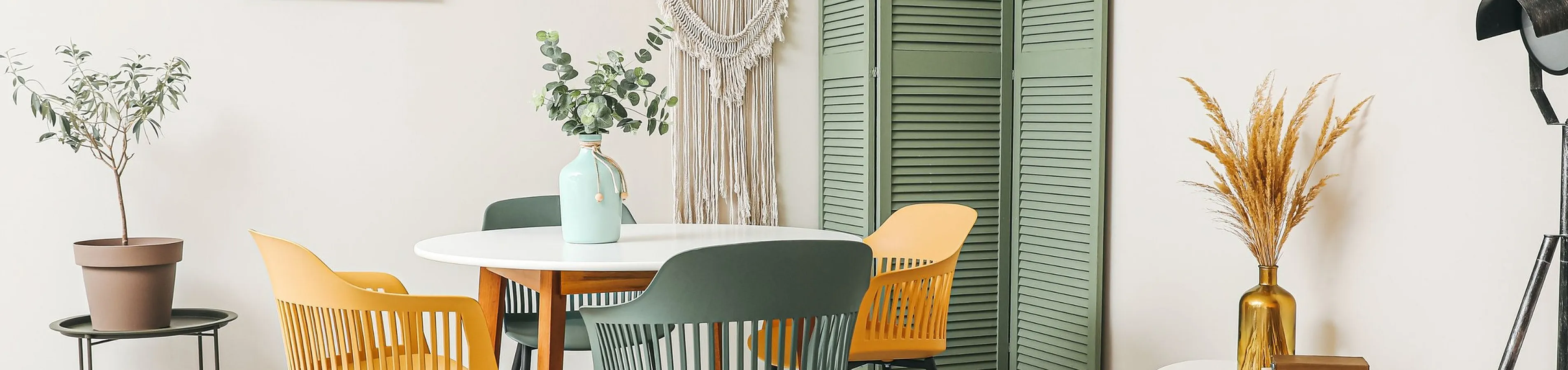 Charming dining area with vibrant chairs around a modern table, accented by artistic decor and lush plants for a stylish and cozy ambiance.