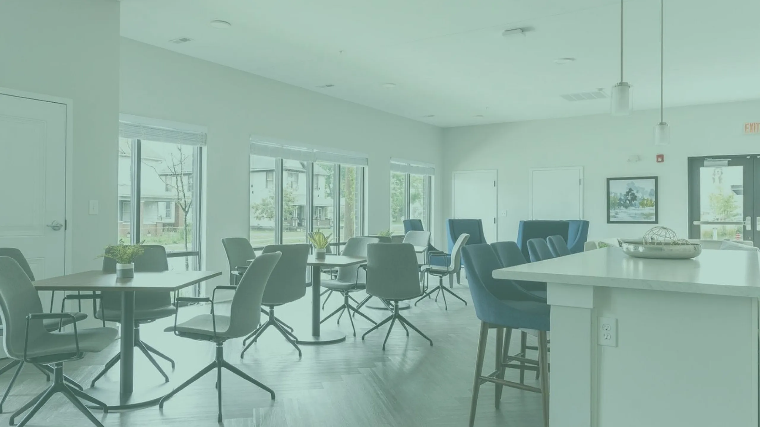 Bright and modern lounge area with stylish chairs, large windows, and a chic countertop, perfect for social gatherings.