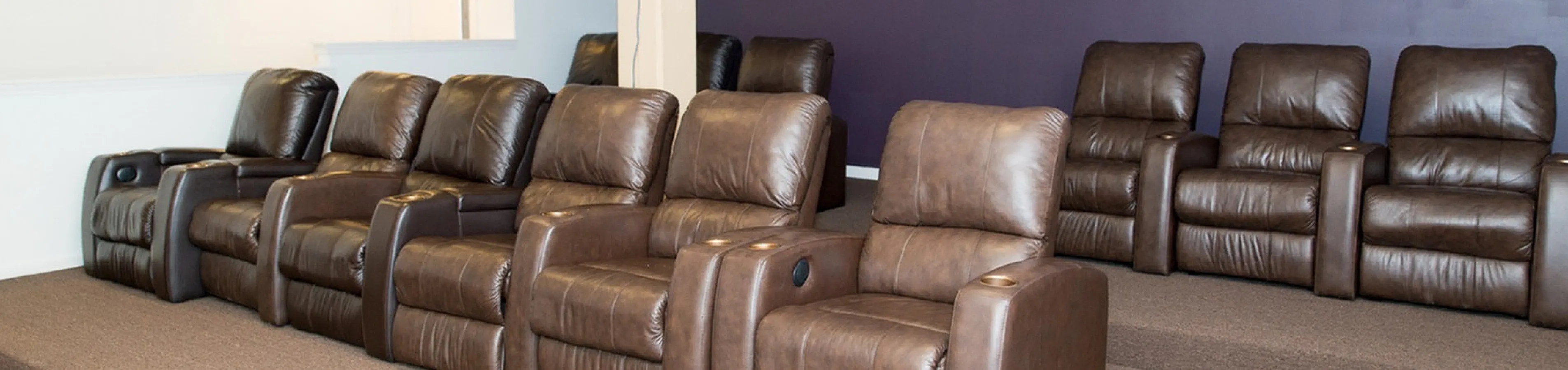 Luxurious home theater with plush brown leather recliners and modern projector, perfect for relaxation and entertainment.
