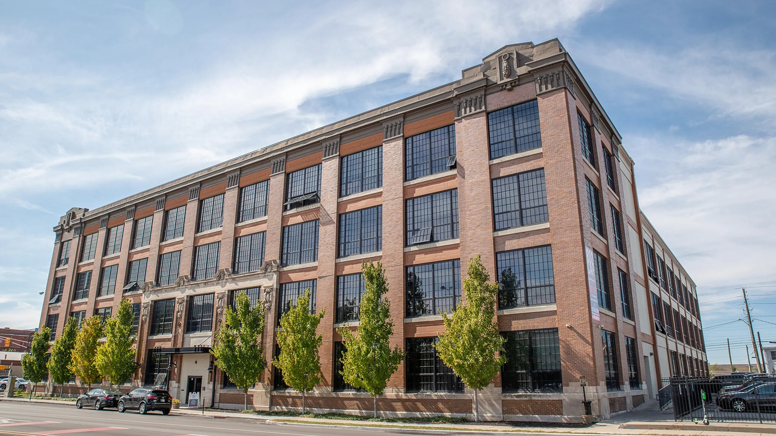 Charming industrial-style apartment building with large windows and modern design elements, set against a clear blue sky.