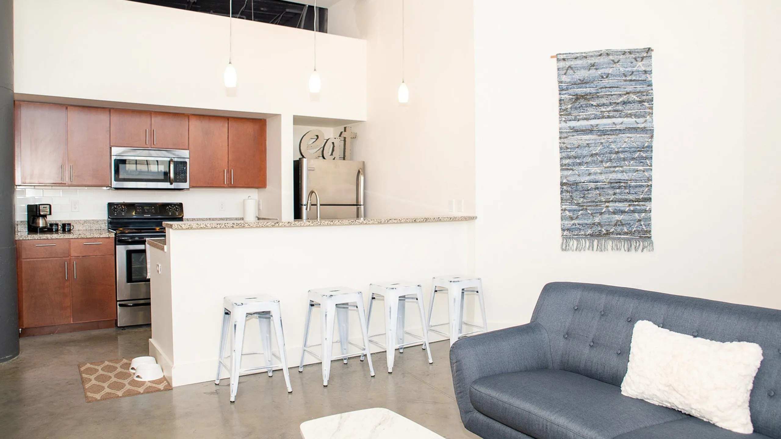 Contemporary kitchen with sleek wooden cabinets, modern appliances, and a stylish breakfast bar with chic pendant lighting in an open-concept living space.