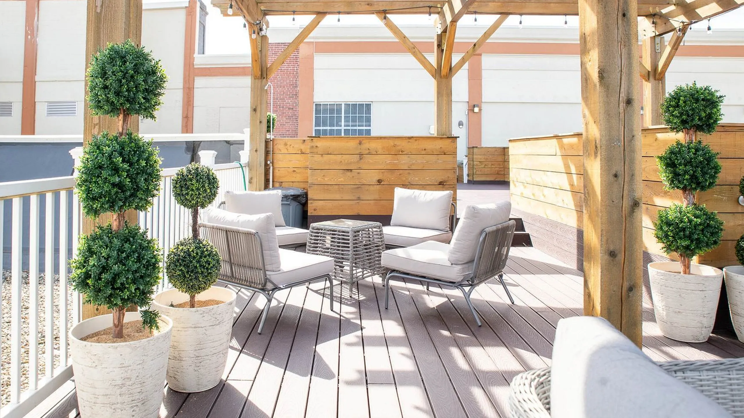 Stylish outdoor patio with cozy seating, potted plants, and a wooden pergola perfect for relaxation.