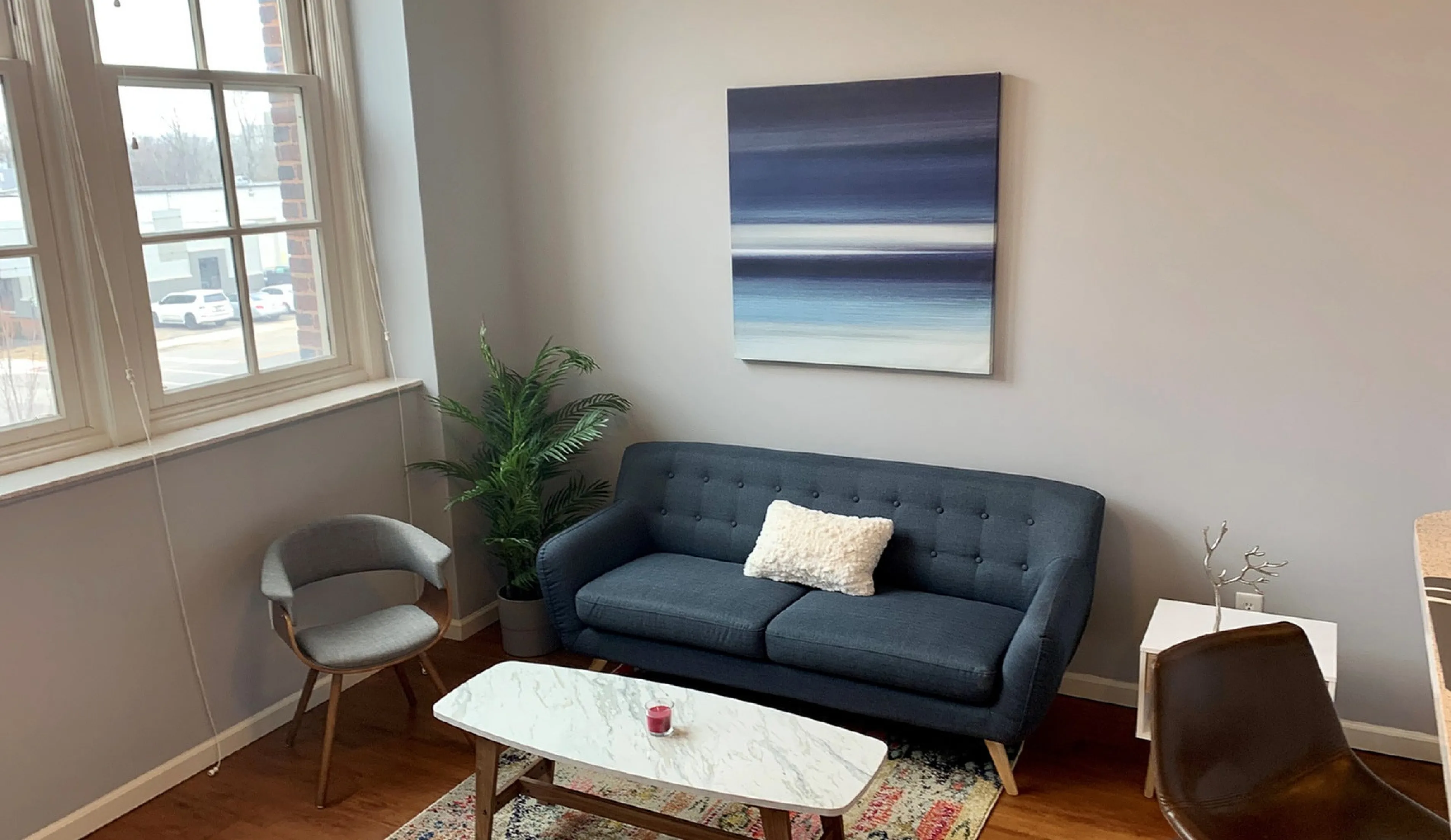 Inviting living room with a chic blue sofa, modern art, elegant coffee table, and large windows for natural light.