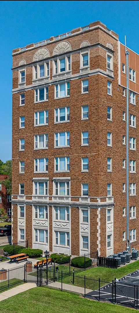 Charming brick apartment building with classic architectural details, nestled in a vibrant neighborhood with ample parking and green outdoor spaces.