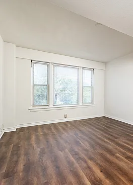 Bright living space with elegant wood flooring and large windows offering abundant natural light.
