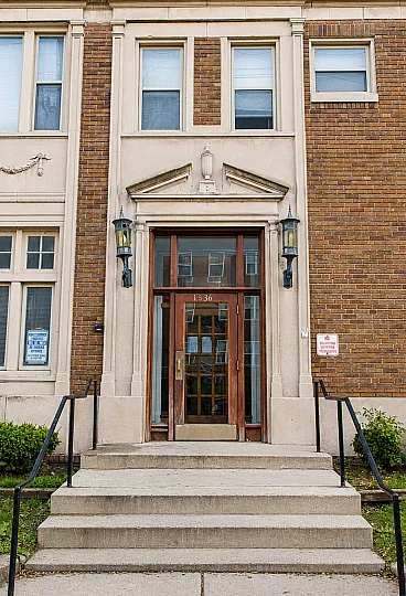 Charming historic brick building entrance with elegant architectural details and welcoming steps.
