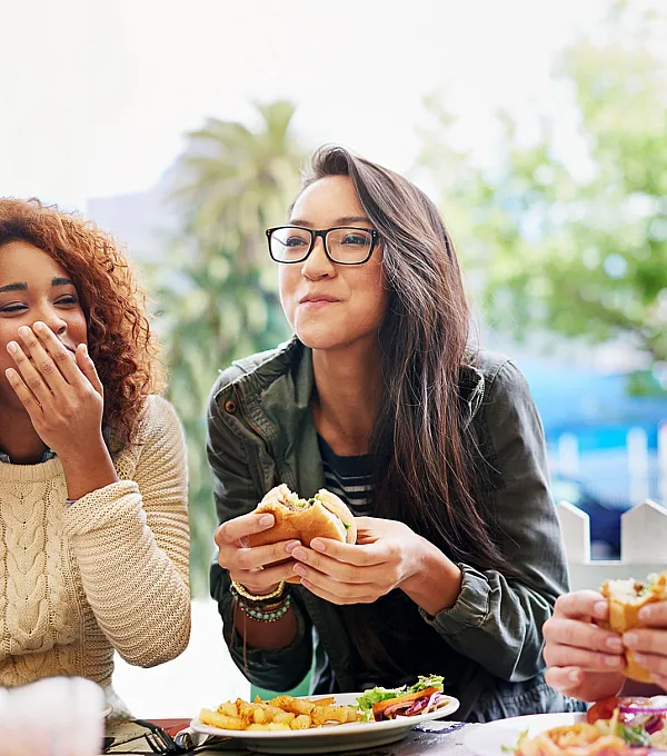 Vibrant outdoor scene with friends enjoying a meal together, showcasing lively conversation and delicious burgers.