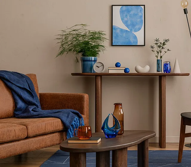Chic modern living room with stylish brown leather sofa, elegant wood furniture, and vibrant blue accents creating a cozy atmosphere.