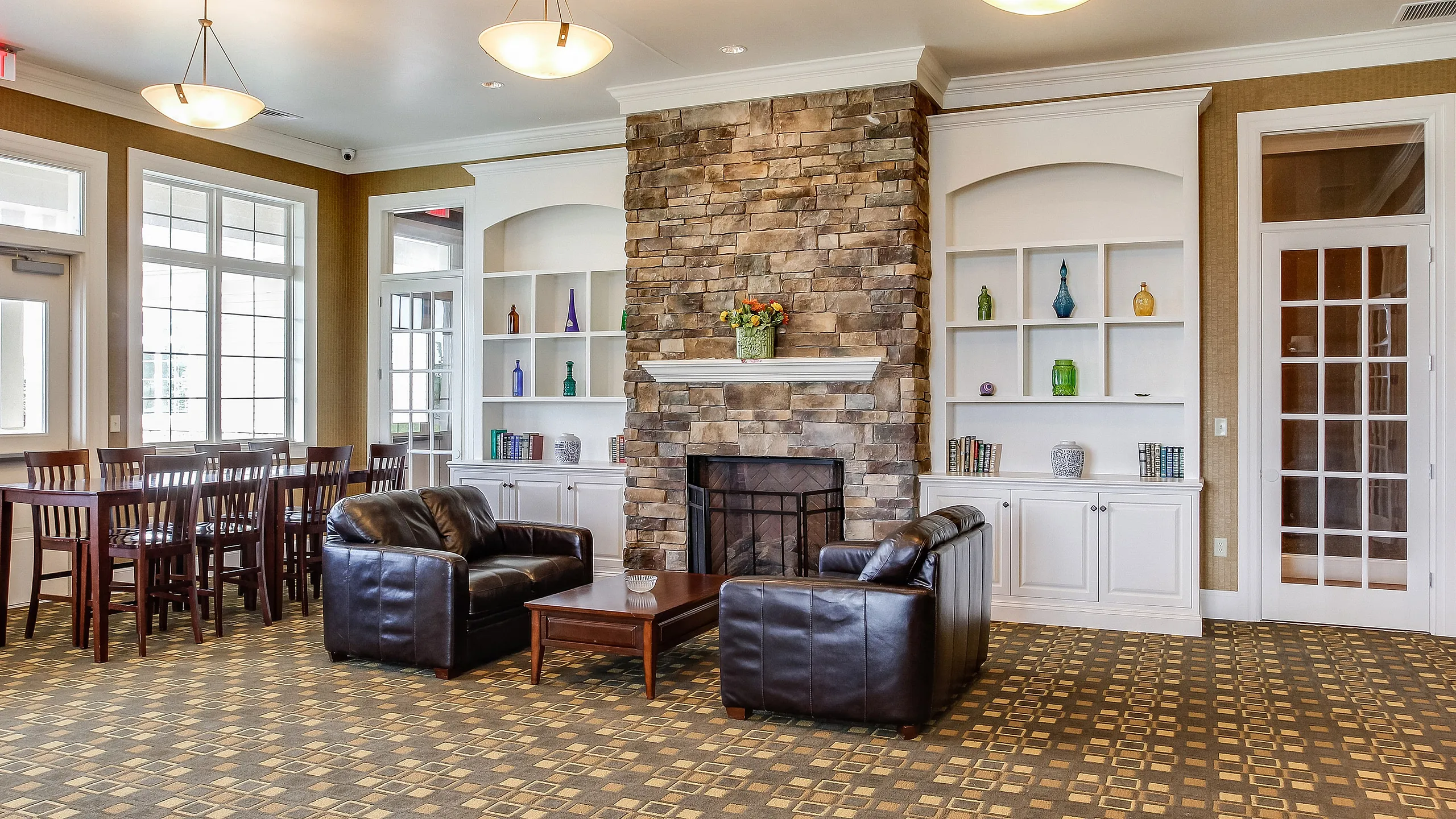 Inviting communal lounge with elegant stone fireplace, comfortable leather seating, and chic wooden dining area, perfect for relaxation and socializing.