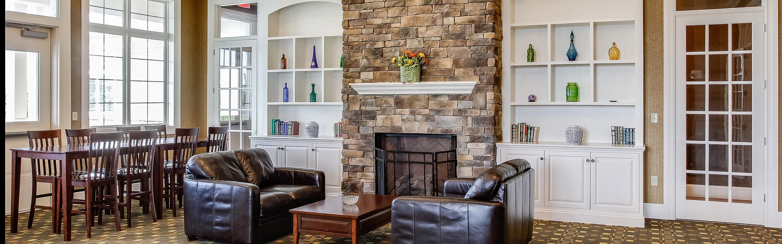 Inviting living area with elegant stone fireplace, leather seating, and stylish built-in shelves displaying vibrant decor.