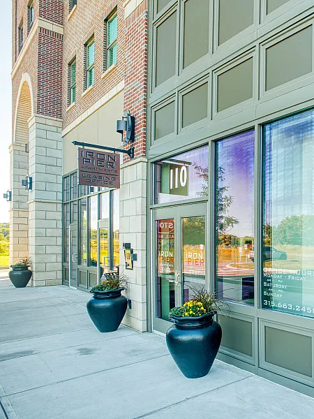 Inviting leasing office entrance with modern glass facade, showcasing greenery and stylish planters.