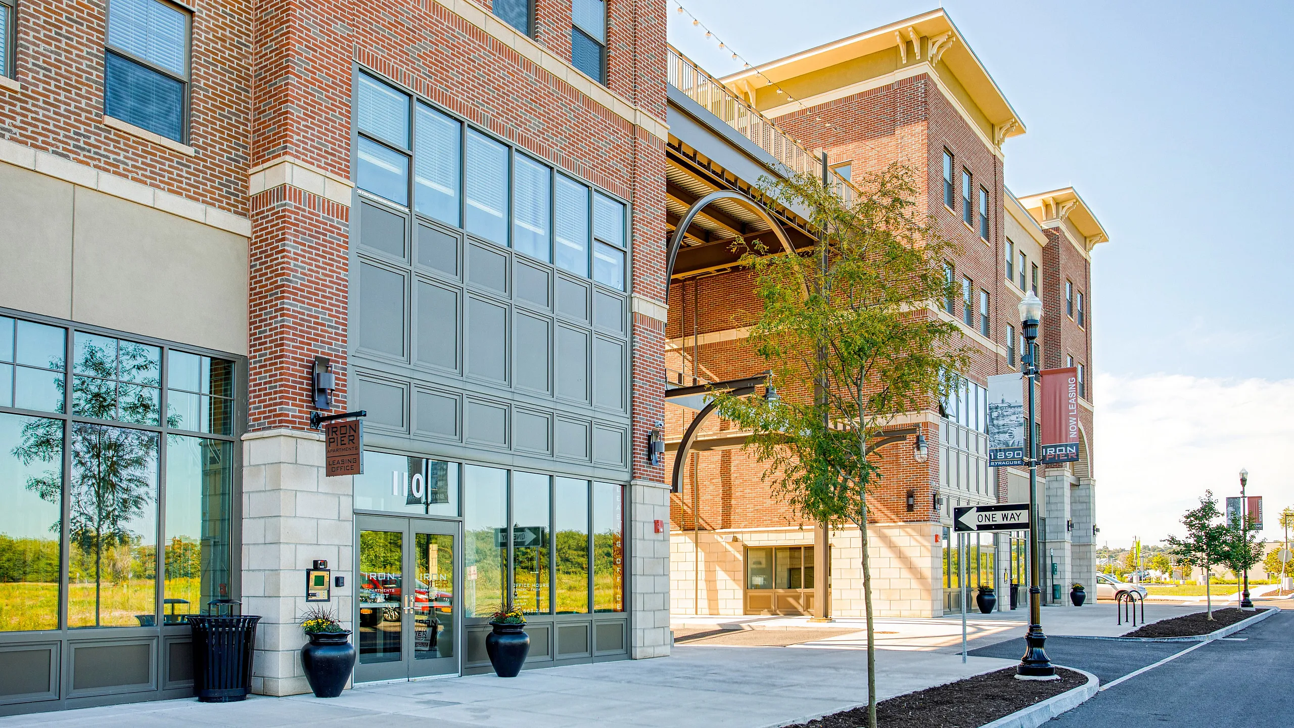 Charming brick-front apartment complex with modern design, large windows, and inviting entrance surrounded by lush trees.