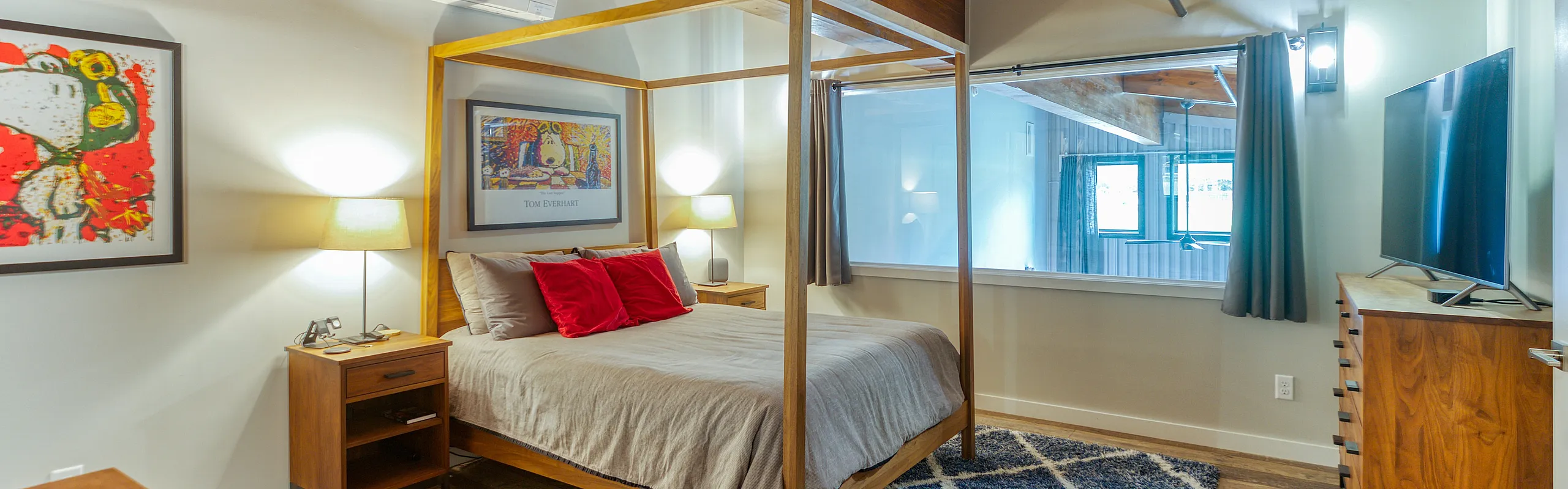 Chic bedroom with a modern four-poster bed, artful decor, and ambient lighting creating a cozy atmosphere.