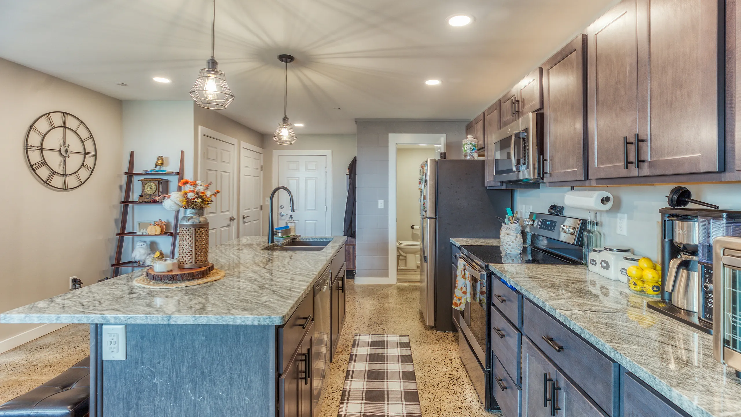 Modern kitchen with sleek granite countertops, stylish pendant lighting, and polished cabinetry offering a functional and elegant design.