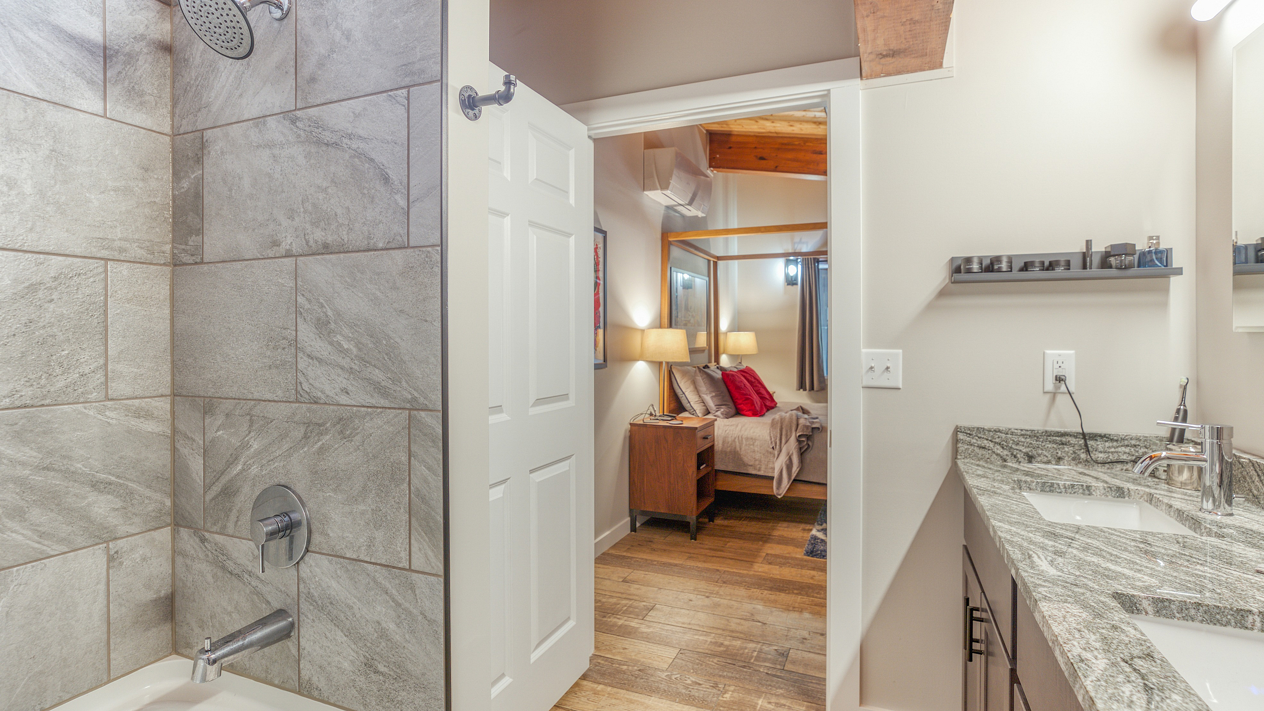 Luxurious bathroom with elegant tile shower leading to a cozy master bedroom featuring warm lighting and stylish decor.