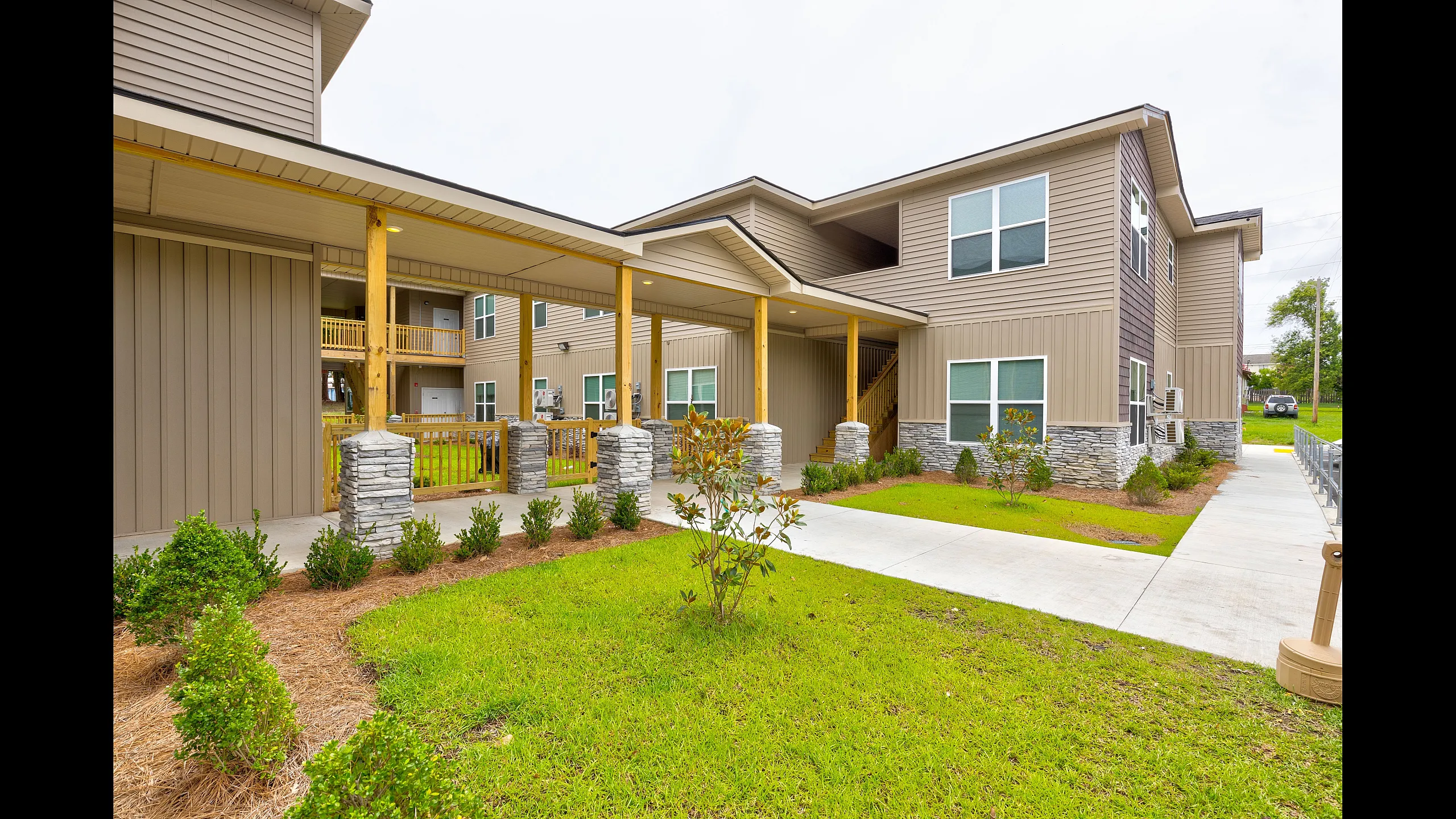 Contemporary apartment complex with charming stone accents and lush landscaping, showcasing a welcoming front entrance and modern architectural design.