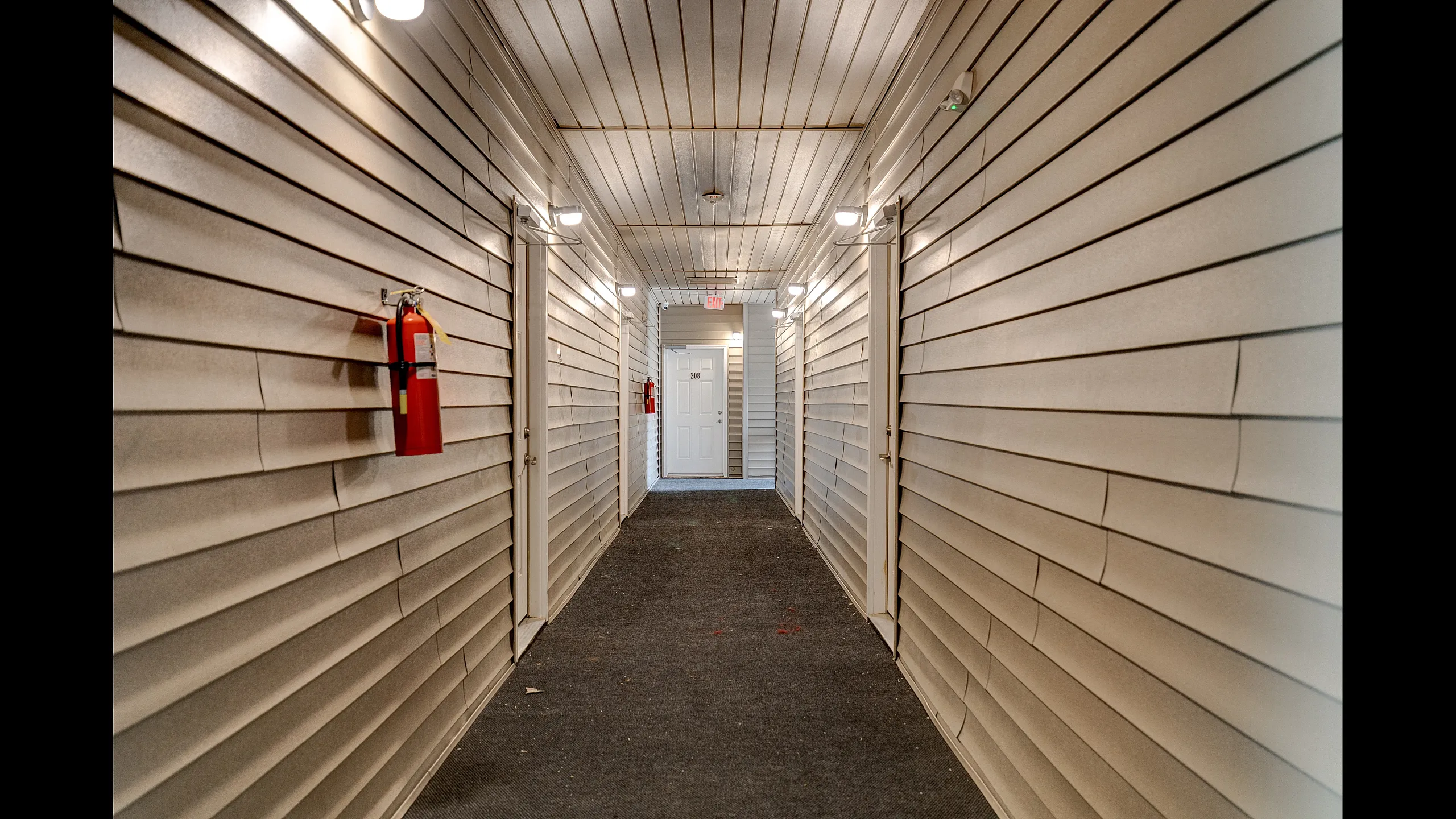 Modern hallway with elegant siding and ample lighting, leading to a secure apartment entrance.