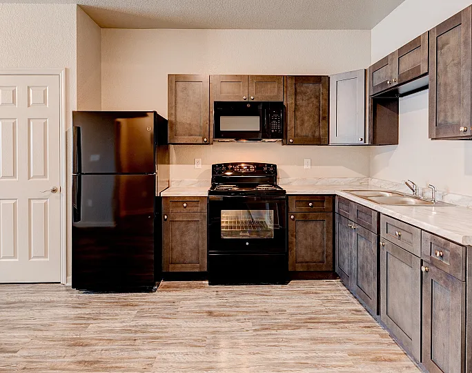 Modern kitchen with sleek black appliances, elegant wooden cabinetry, and stylish laminate flooring.