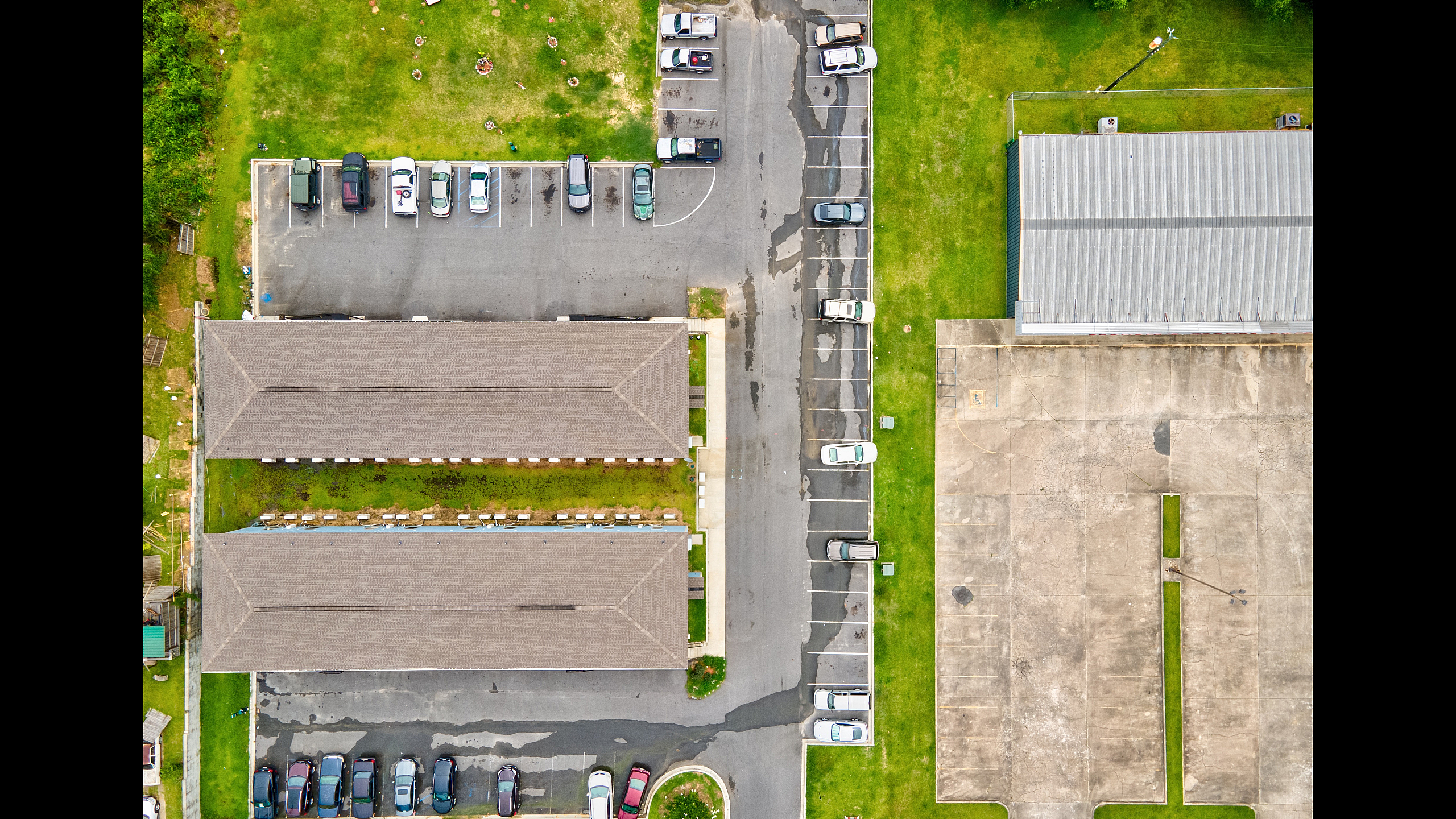 Aerial view of modern apartment complex with ample parking and green spaces, showcasing convenience and tranquility.