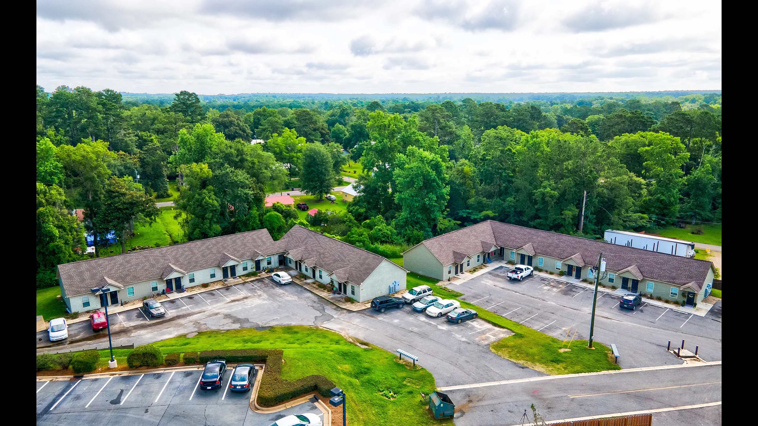 Charming apartment complex nestled in lush greenery, offering serene living with ample parking and a welcoming community atmosphere.