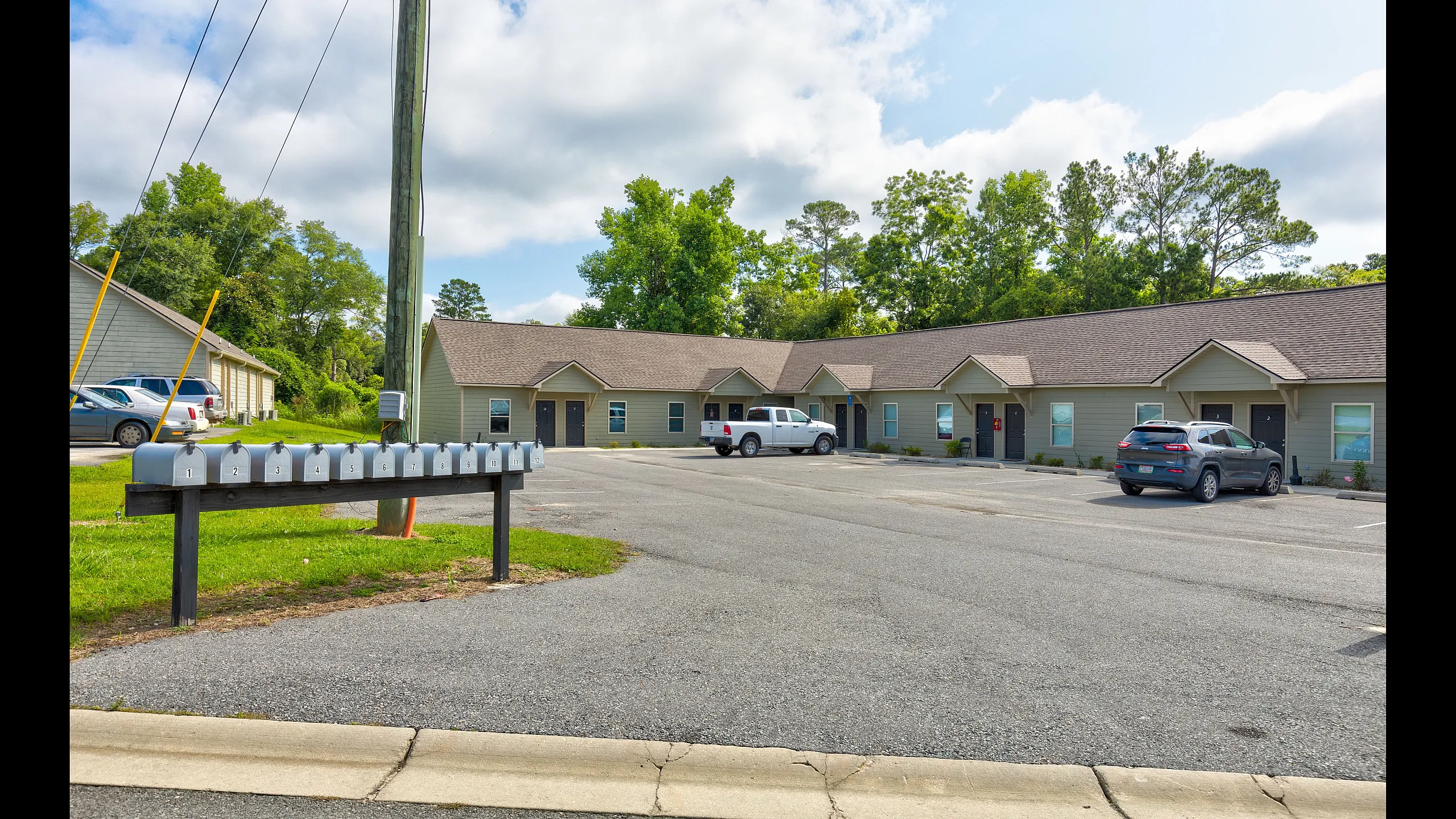 Charming apartment complex with ample parking and lush greenery, offering a peaceful residential ambiance.