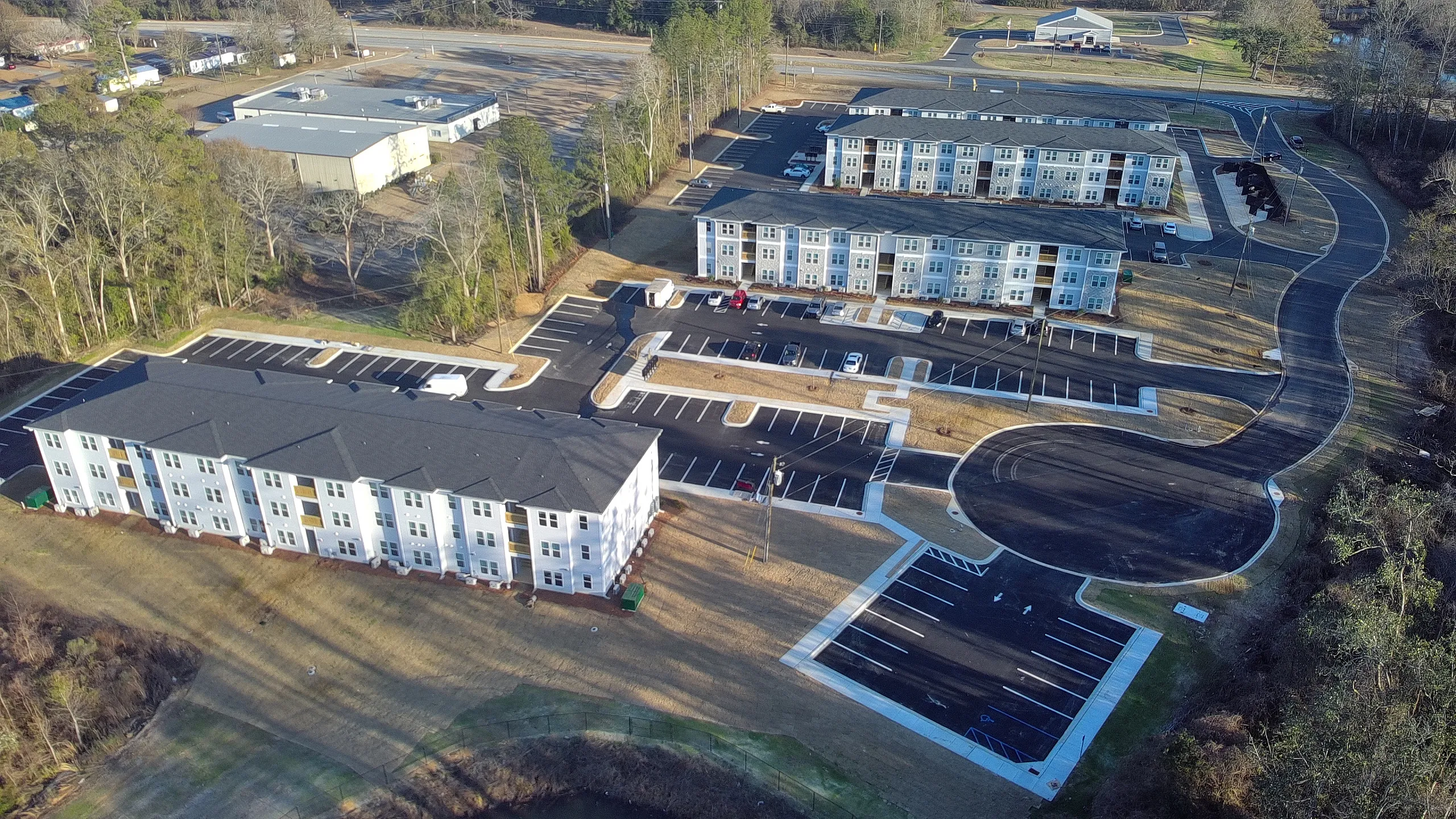 Modern apartment complex with spacious parking, surrounded by lush greenery and a scenic view, offering a peaceful residential environment.