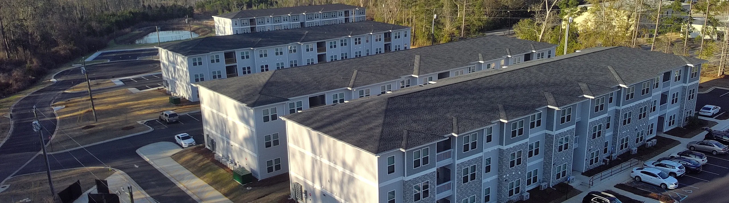 Charming apartment complex surrounded by lush greenery, featuring modern architecture and spacious parking, perfect for serene living.
