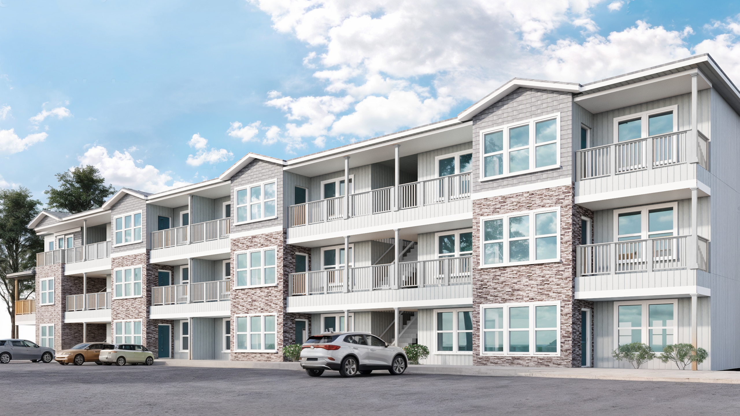 Modern three-story apartment complex with spacious balconies, elegant stone detailing, and ample parking under a bright blue sky.
