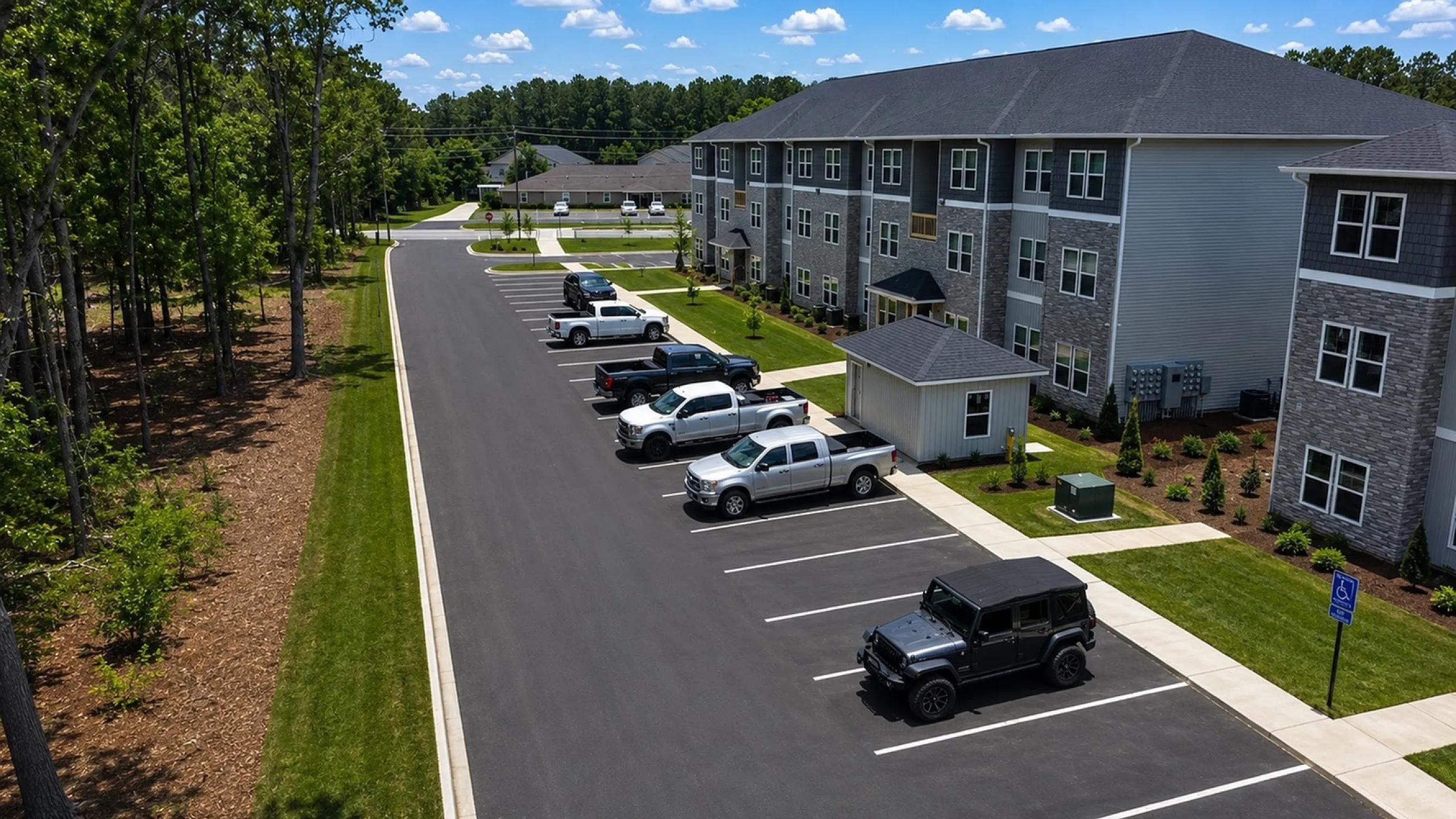 Modern apartment complex with ample parking and lush greenery, offering a serene and convenient living environment.